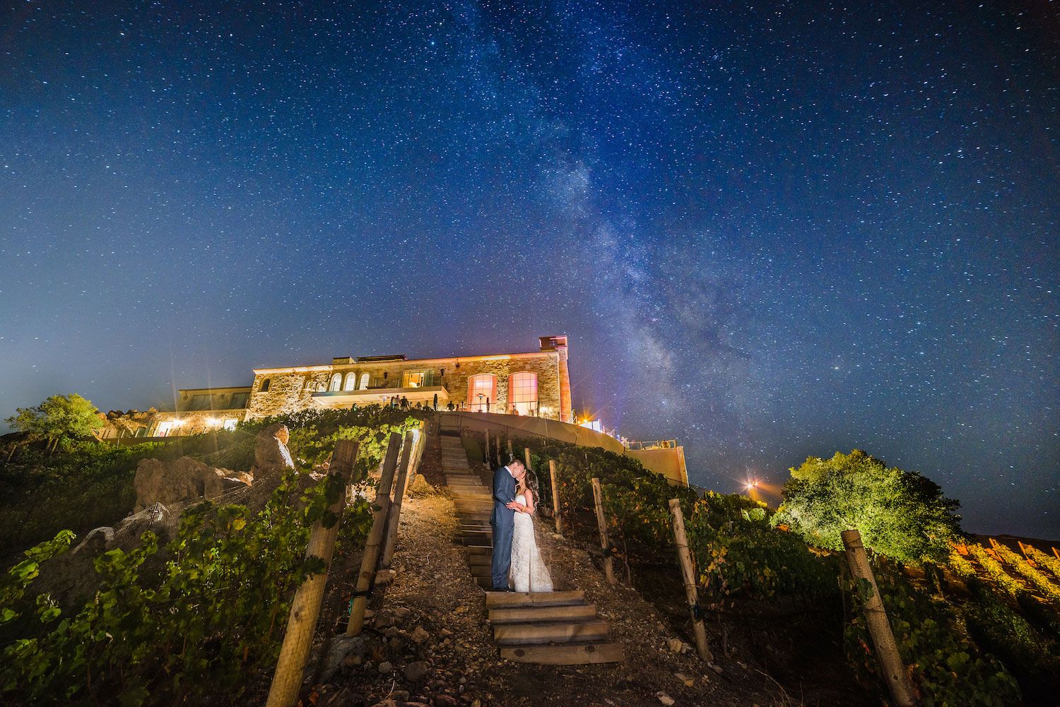 Creative nighttime wedding portrait with the venue as a dramatic backdrop