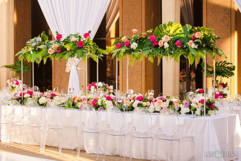 Stately and stylized white tables with delicately adorned roses and ferns on a catering table during a wedding at the San Diego Museum of Art , located in California 