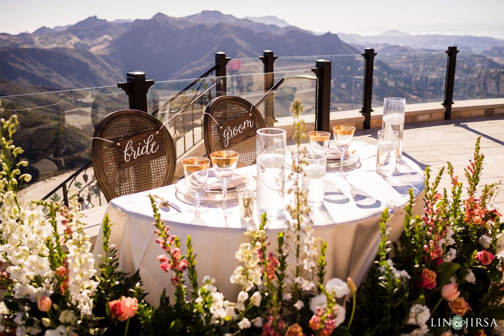 Bride and groom sweetheart table at the Malibu Rocky Oaks estate wedding venue with pink and white snapdragons, surrounding the table with the rocky mountains in the background