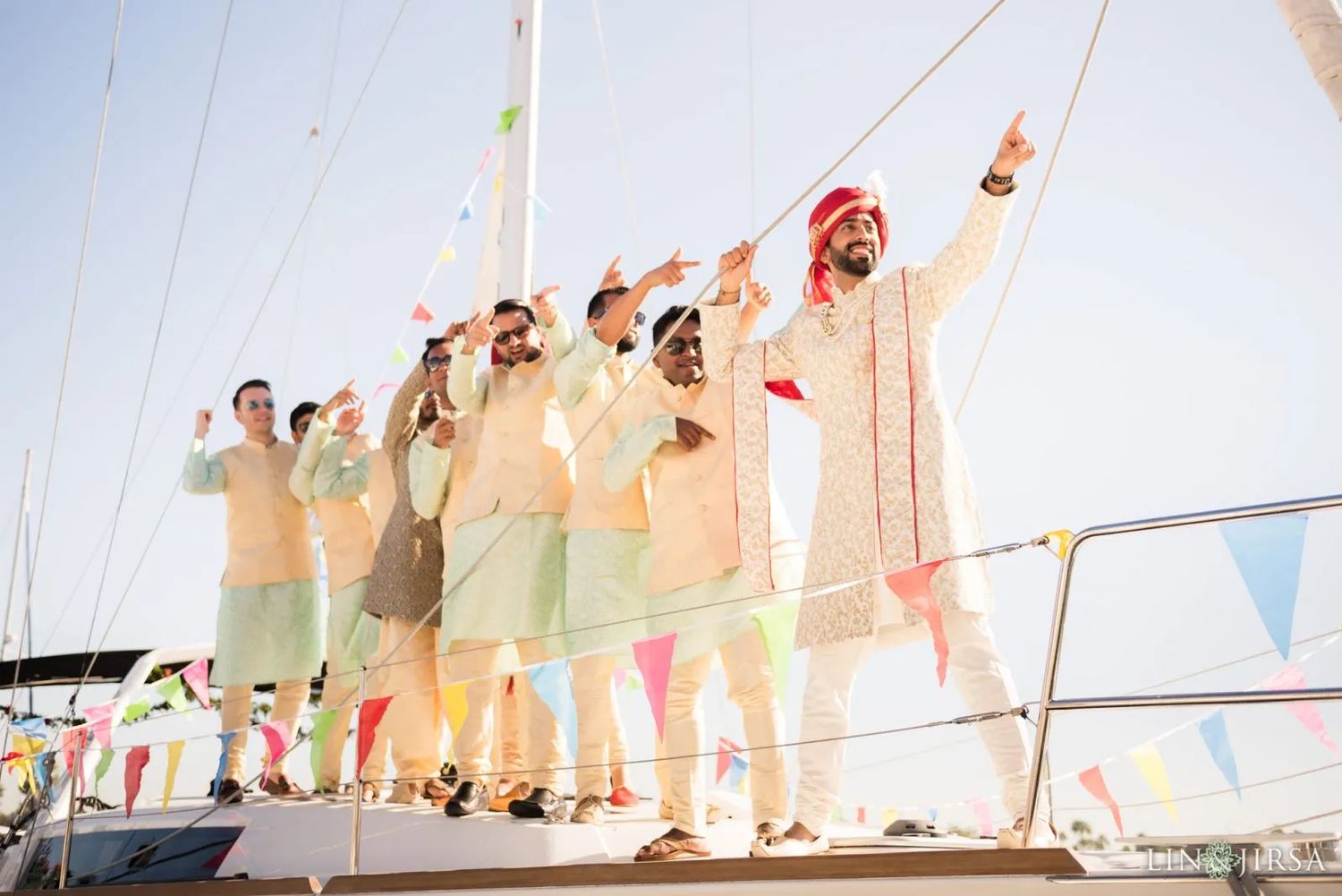 Groom arriving in celebration surrounded by family and friends dancing to the dhol during the Baraat procession
